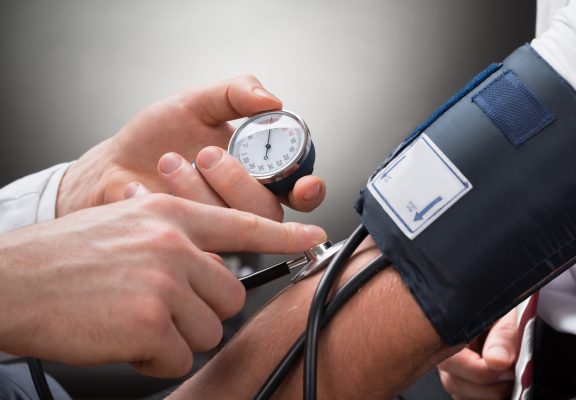 Close-up Of A Doctor's Hand Checking Blood Pressure Of A Patient